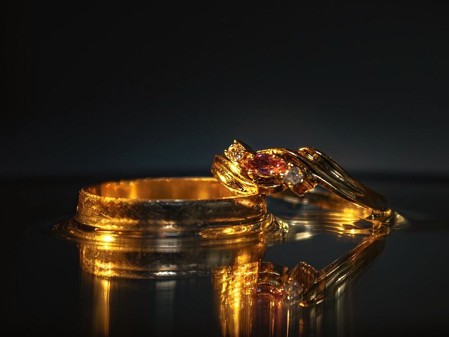 Gold rings and bands catching warm light on a dark surface