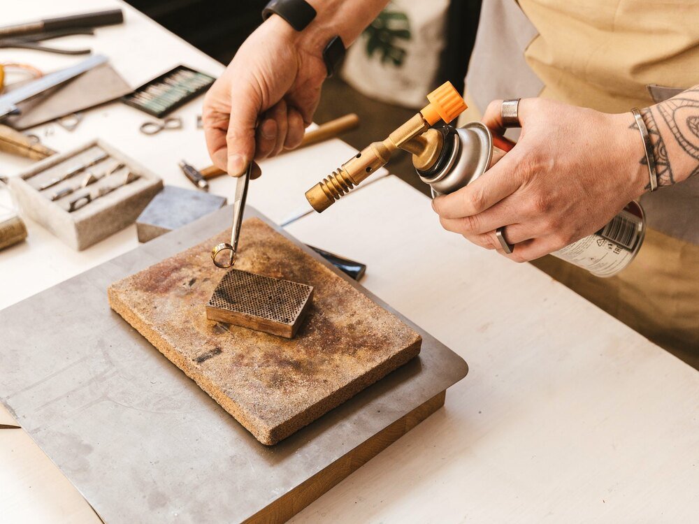 A jeweller soldering a piece at the bench