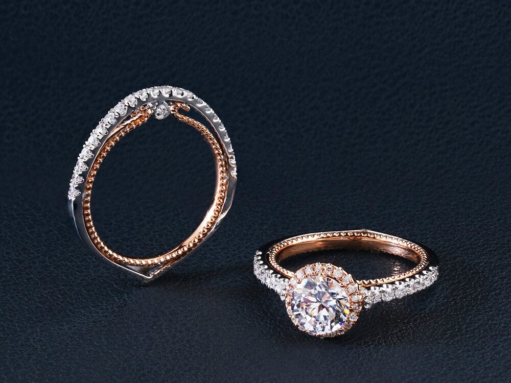 A rose gold diamond engagement ring and matching band on a dark ground