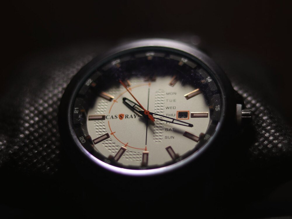 Close-up of a wristwatch face on a dark ground